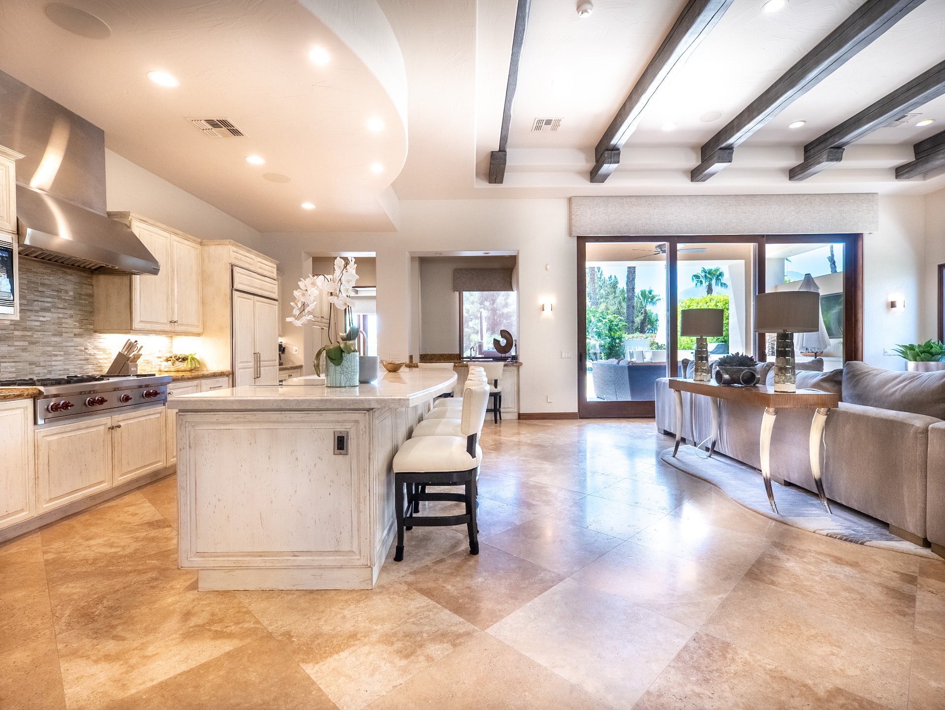 Open kitchen and great room with travertine floors and pocketing glass doors