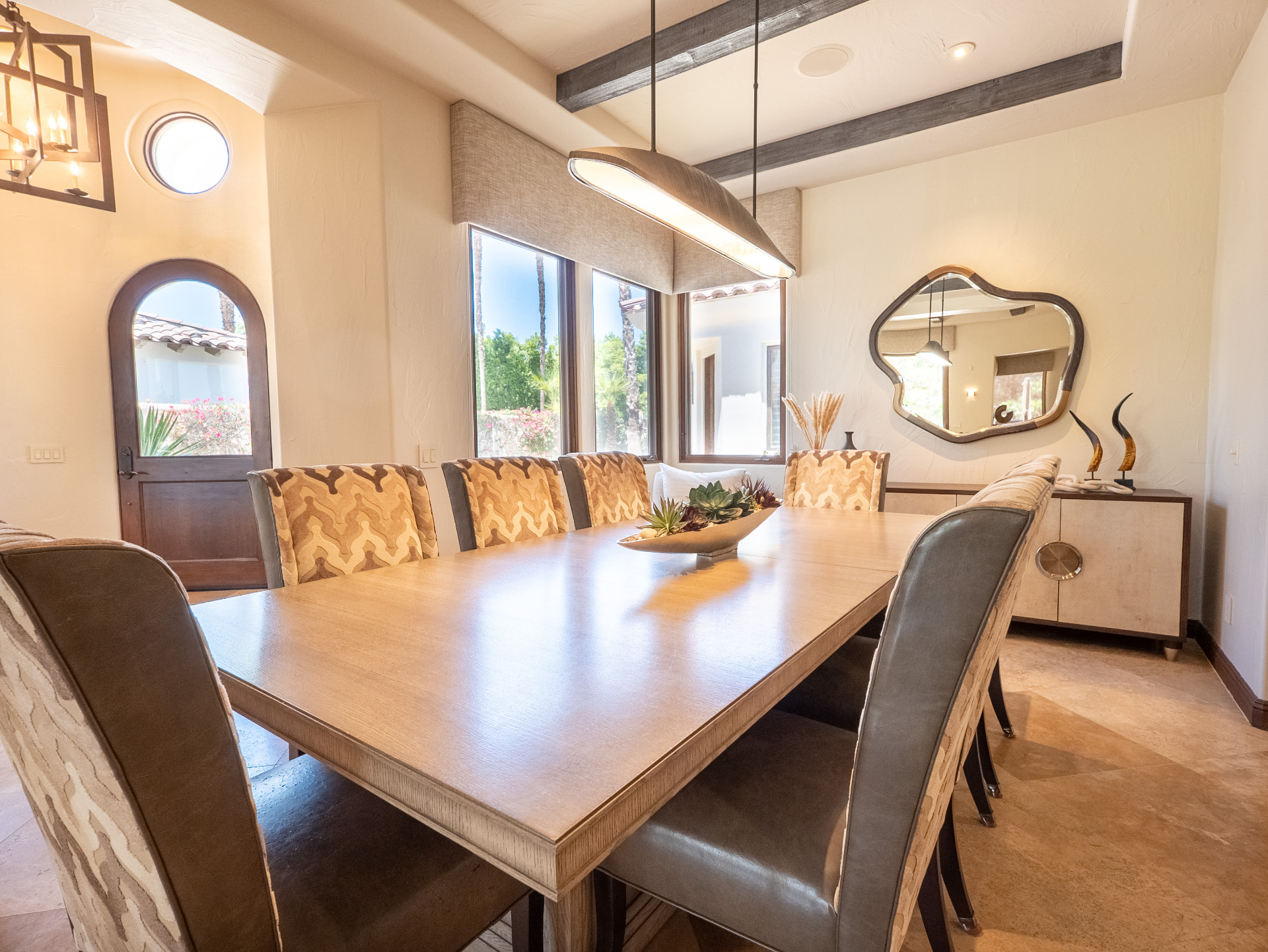Formal dining room seating eight beneath wood beams and linen pendant