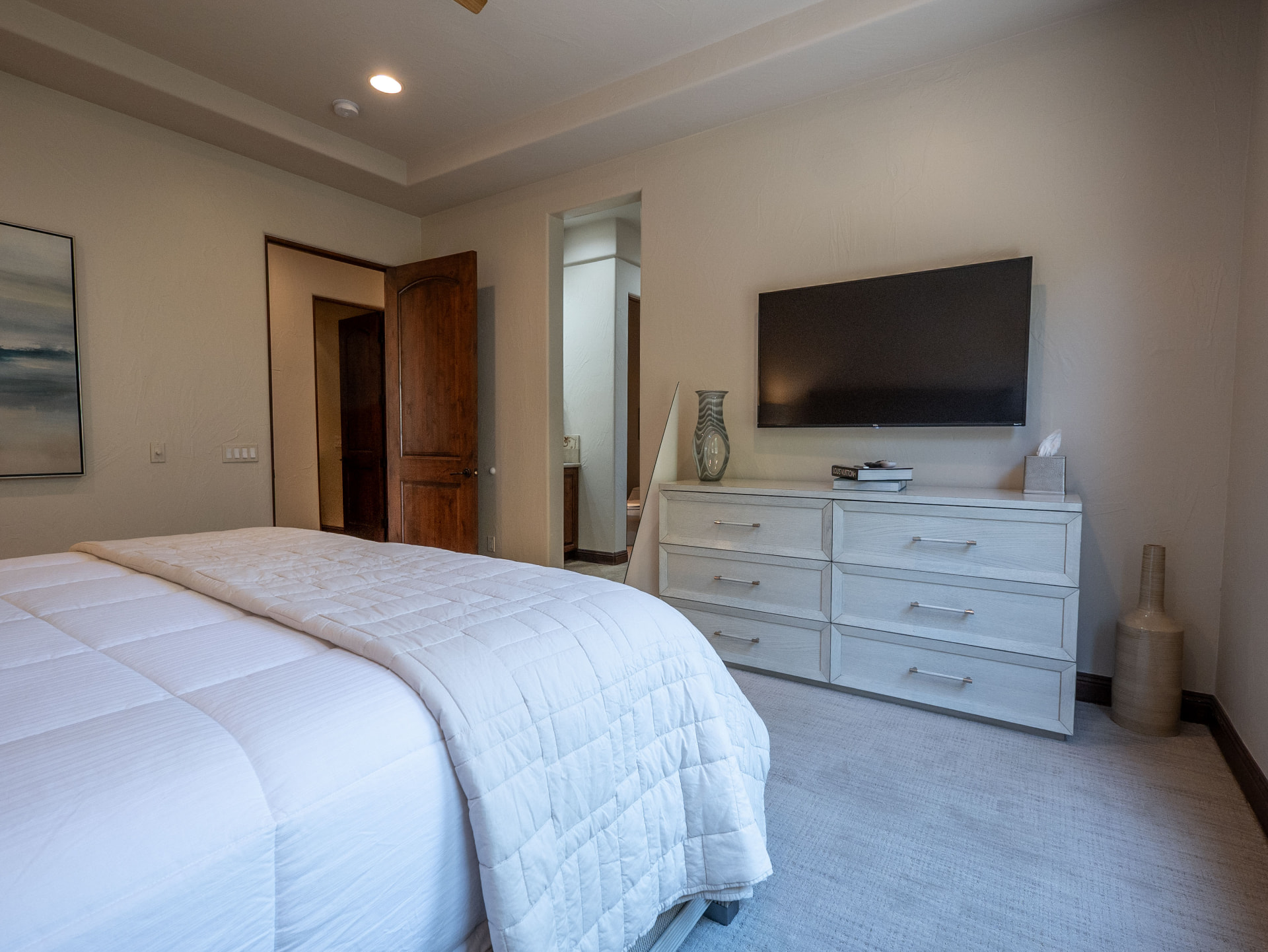 Bedroom with wall-mounted television, dresser and ensuite entry