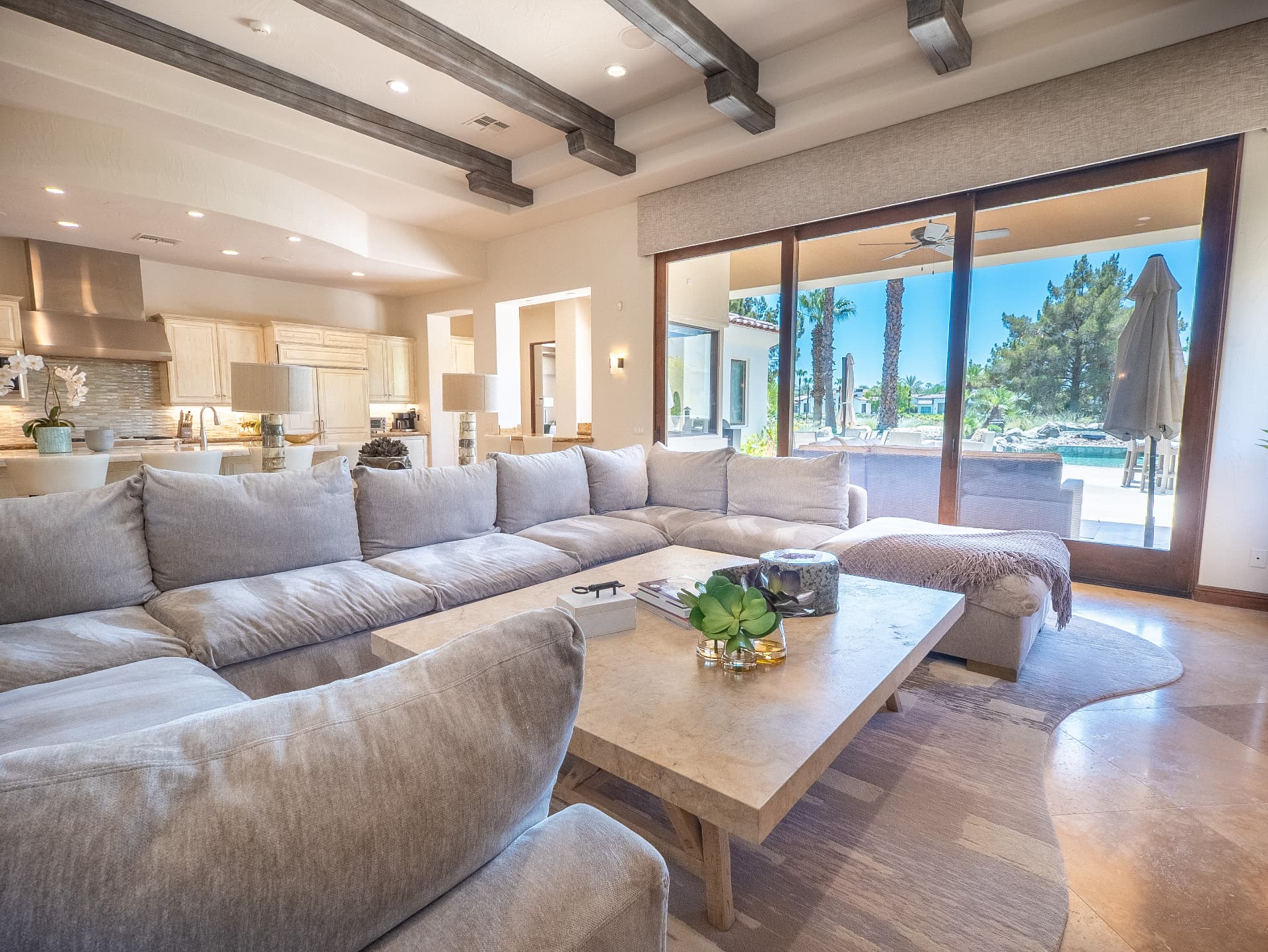 Great room with sliding glass doors framing the pool and palms