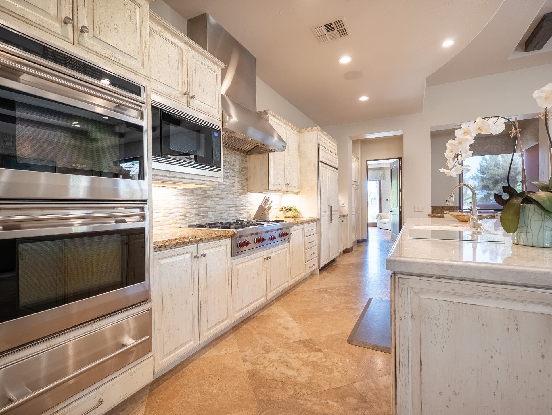 Kitchen galley with Wolf range, double ovens and glass tile backsplash