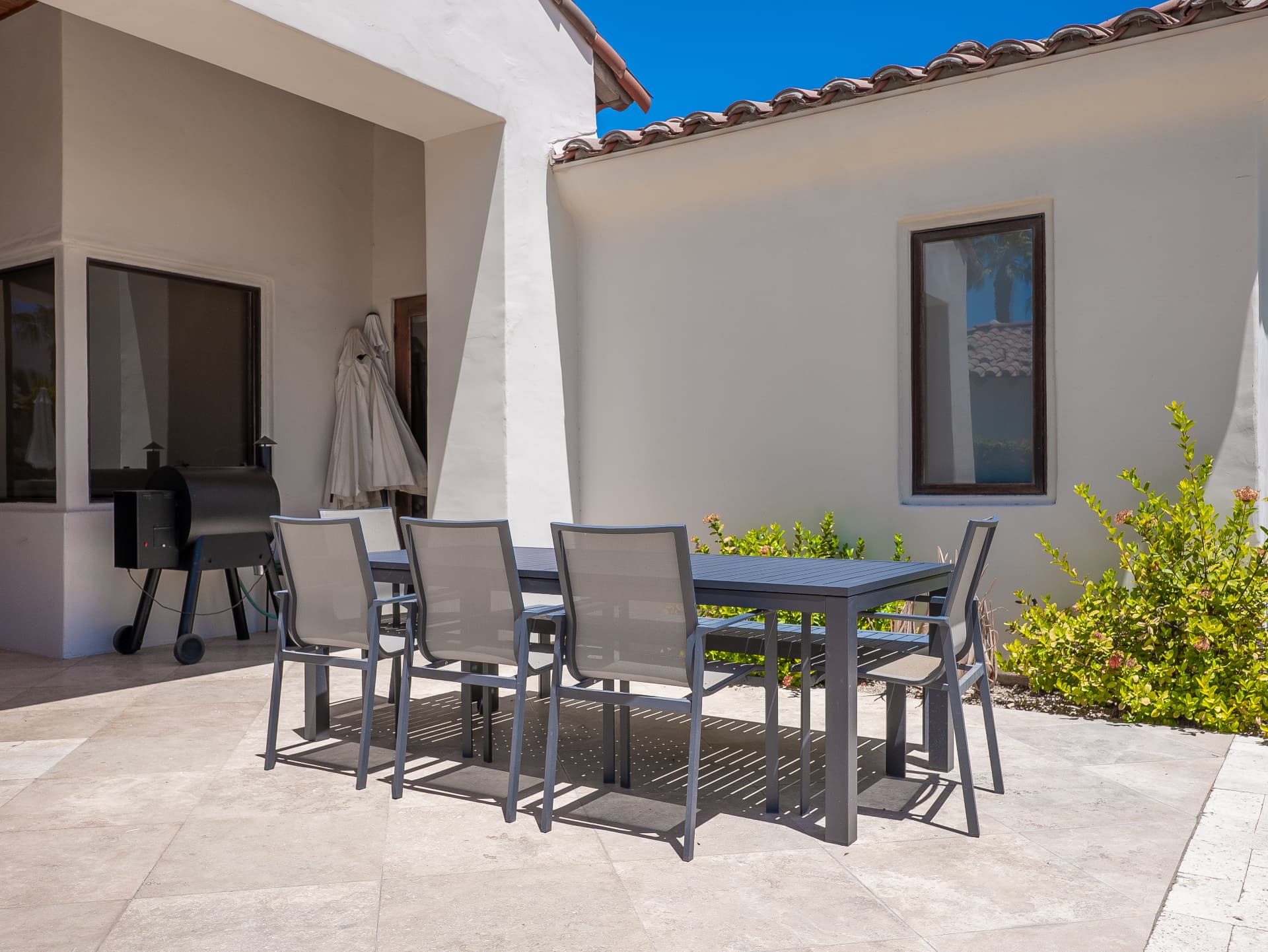 Courtyard dining terrace with grill and smoker beneath tile roofline