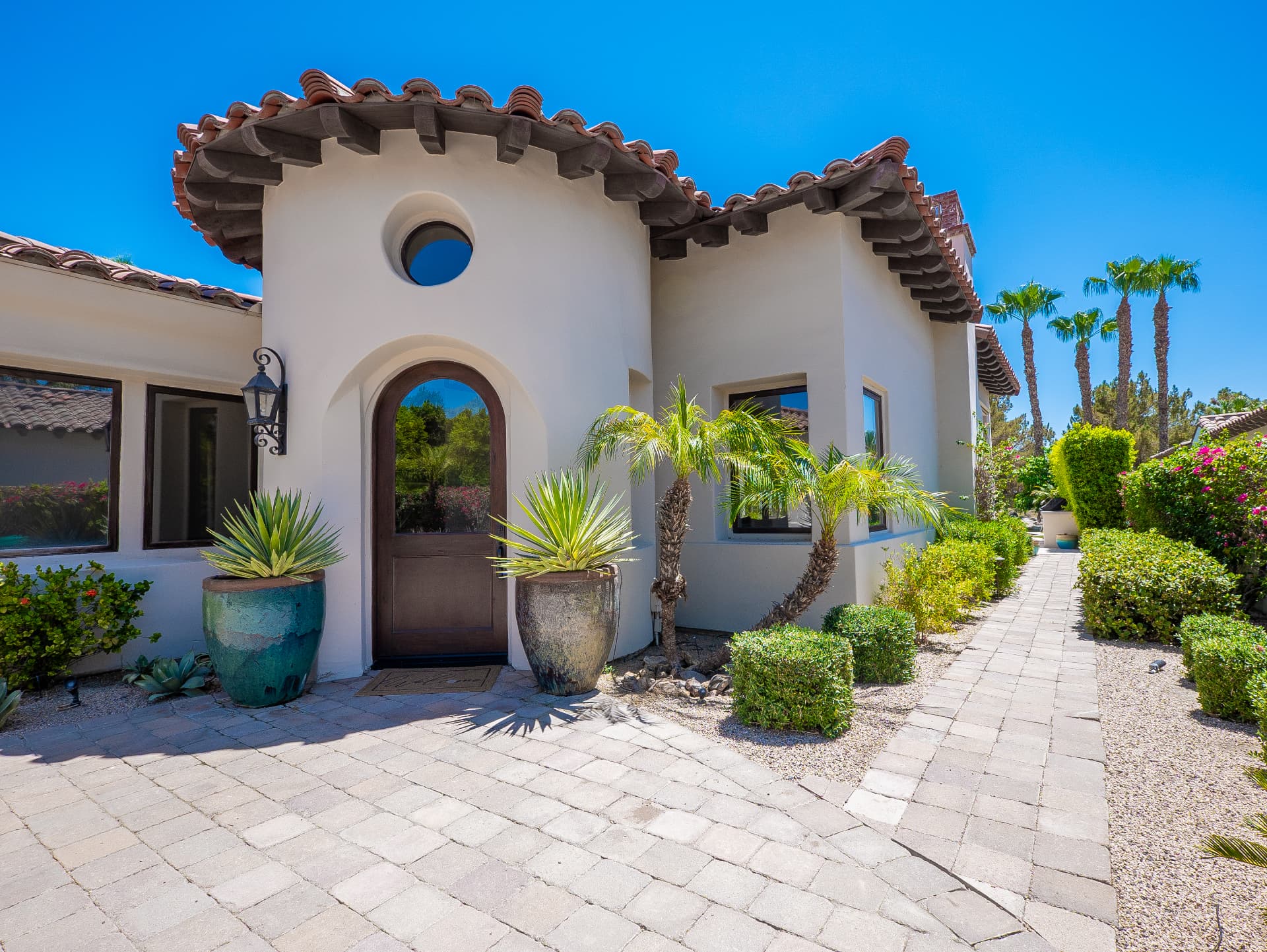 Arched wood front door with turret entry and glazed planters