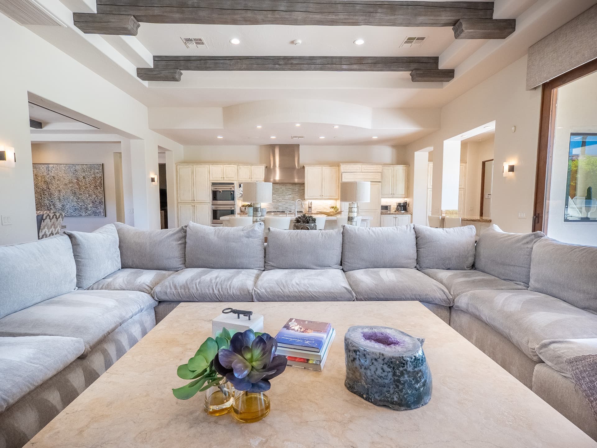 Living room seating open to the kitchen beneath wood beams