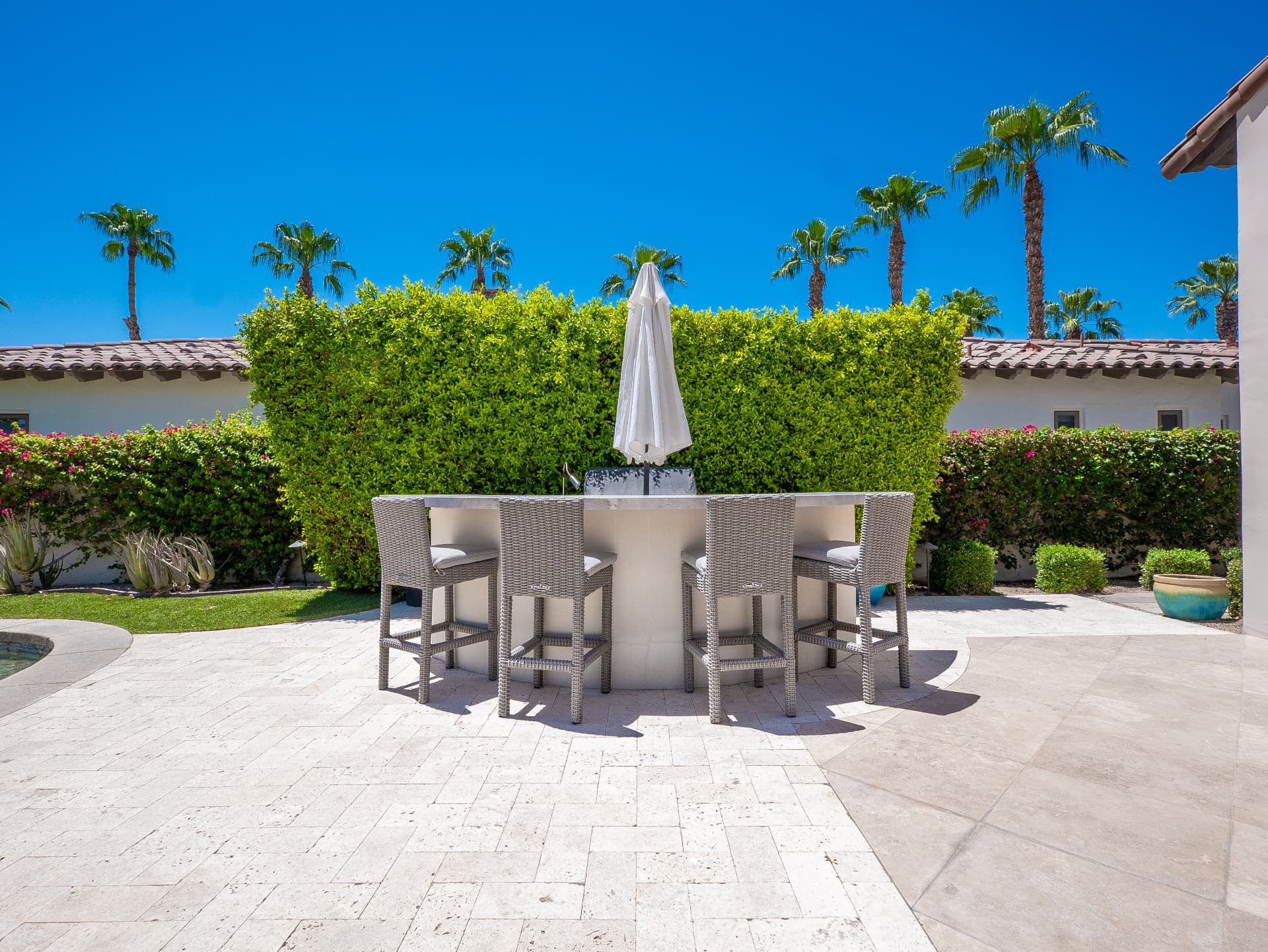Outdoor bar with counter seating and hedged garden backdrop