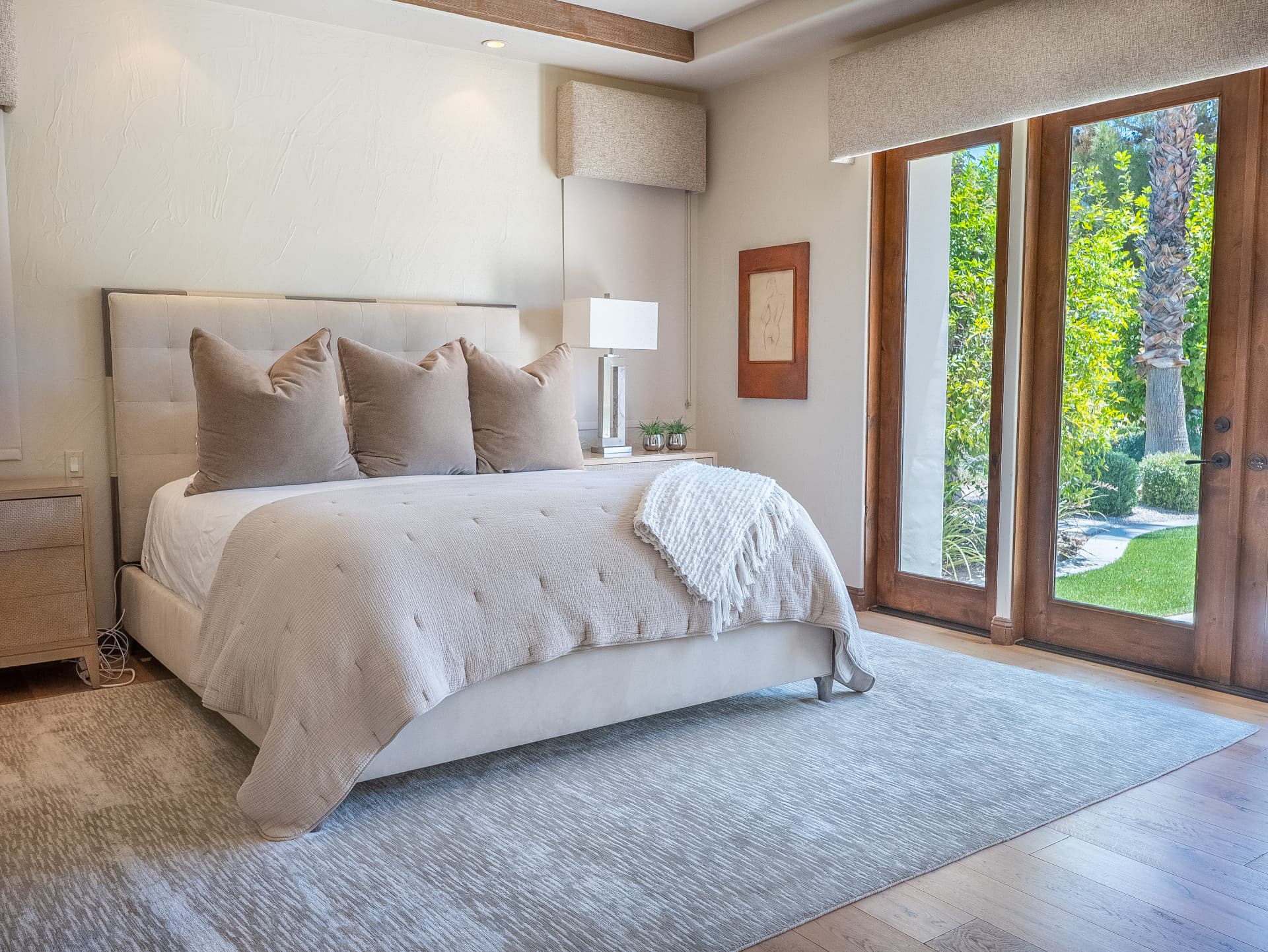 Primary bedroom with upholstered king bed and doors to the courtyard