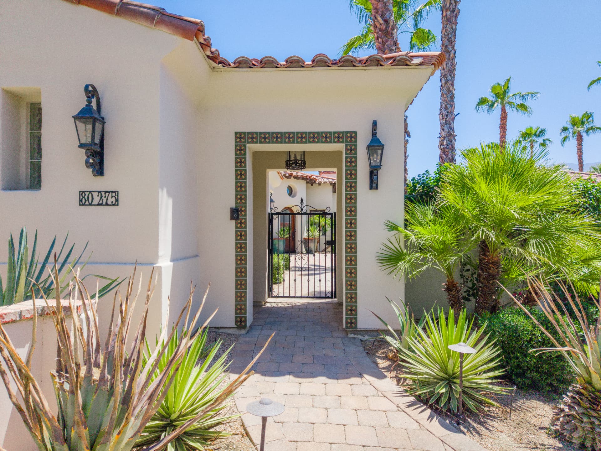 Hand-painted tile entry surround with wrought iron gate and lanterns