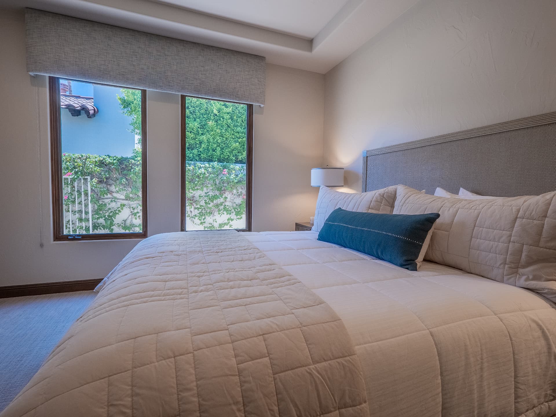 Corner bedroom with linen bedding and courtyard windows