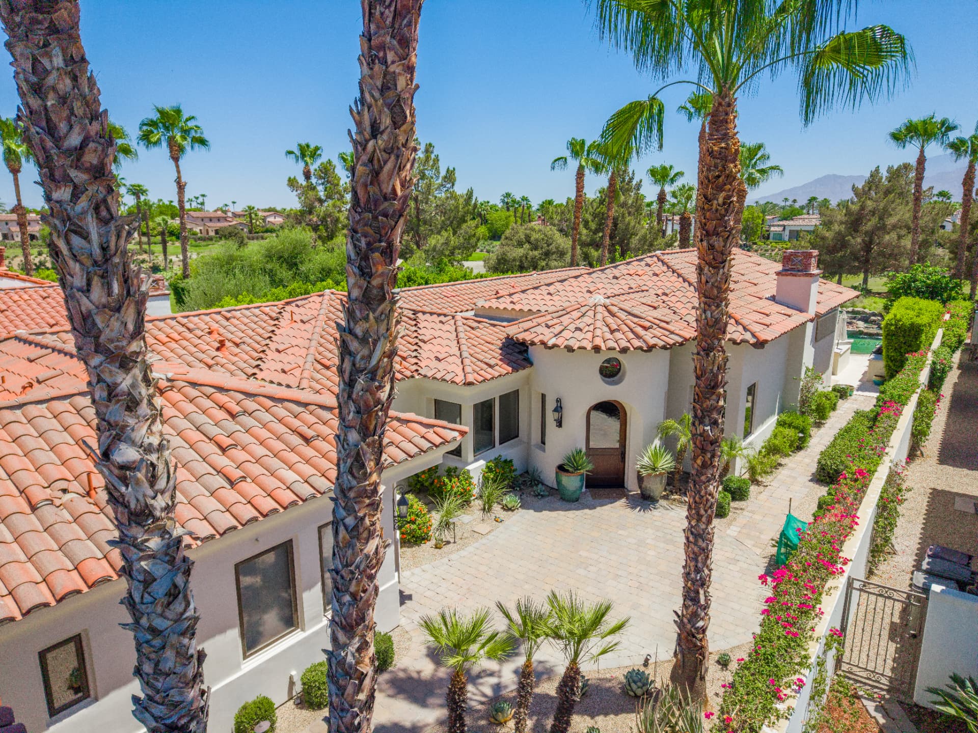 Arched front door and paved courtyard framed by palms