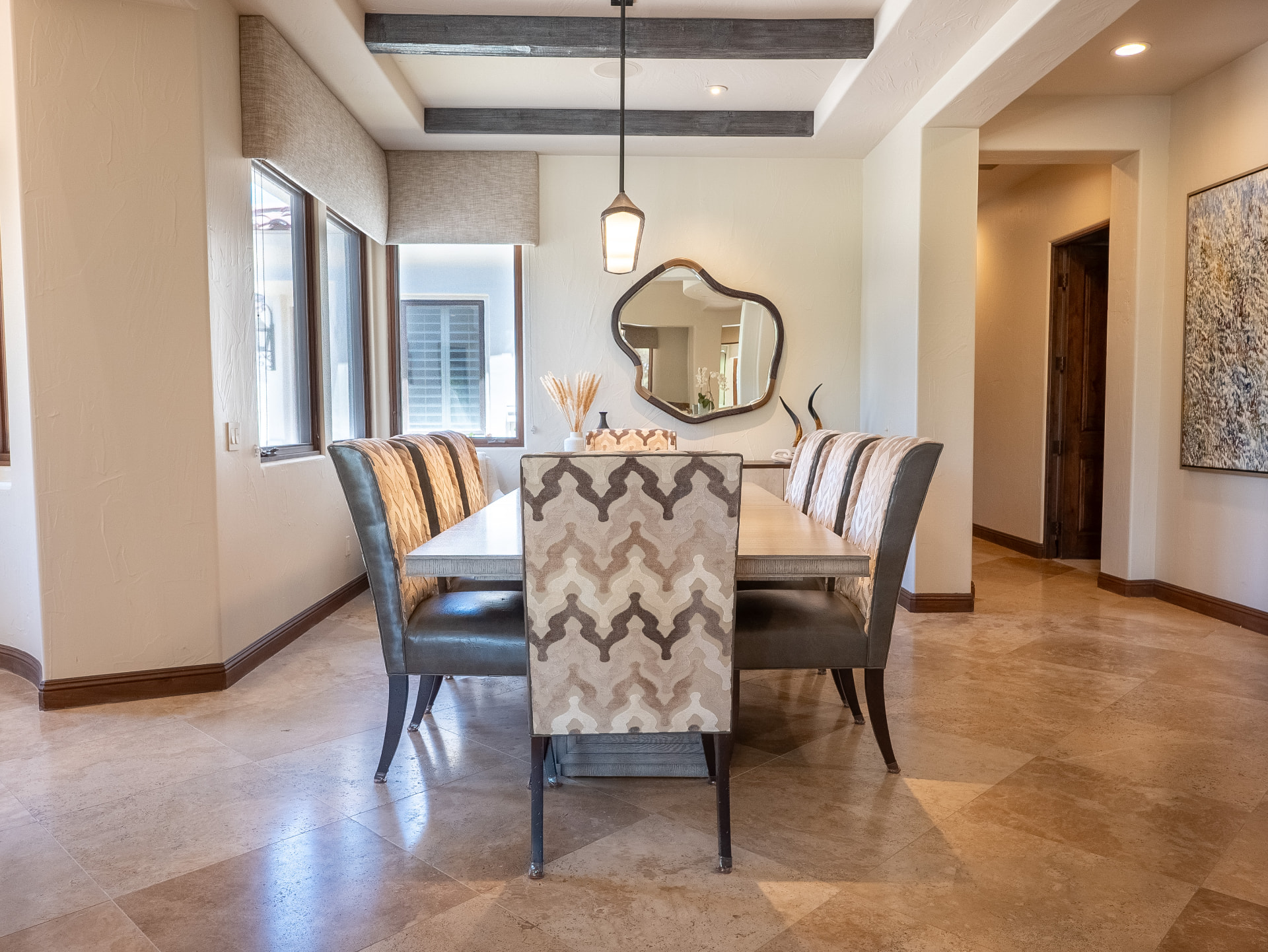 Dining room with organic mirror, beamed ceiling and travertine floors