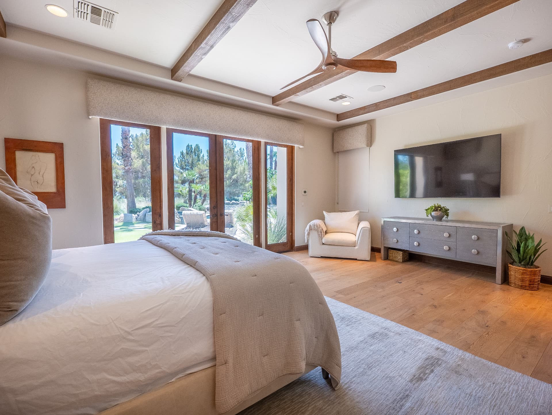Spacious bedroom with beamed ceiling, ceiling fan and garden doors