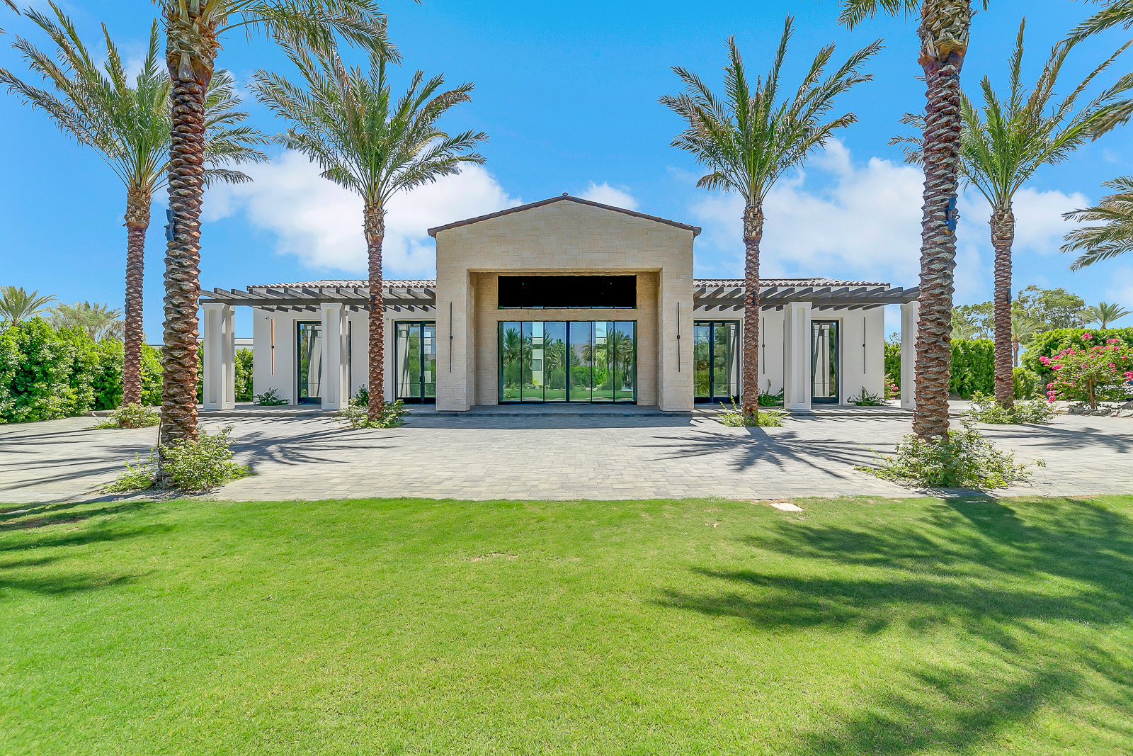 Elegant desert estate entrance with palm trees and manicured lawn