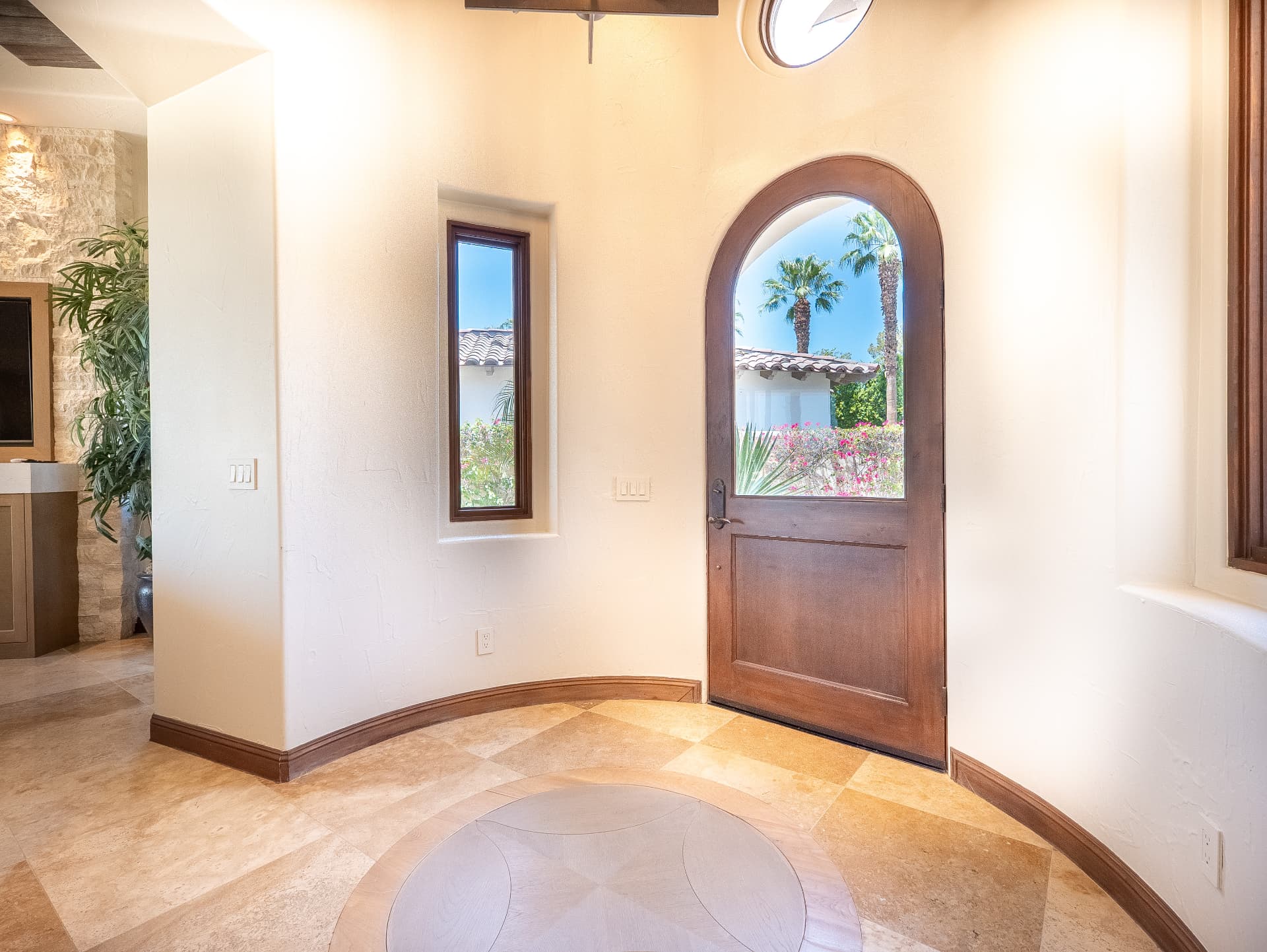 Arched wood entry door and travertine foyer with stone accents