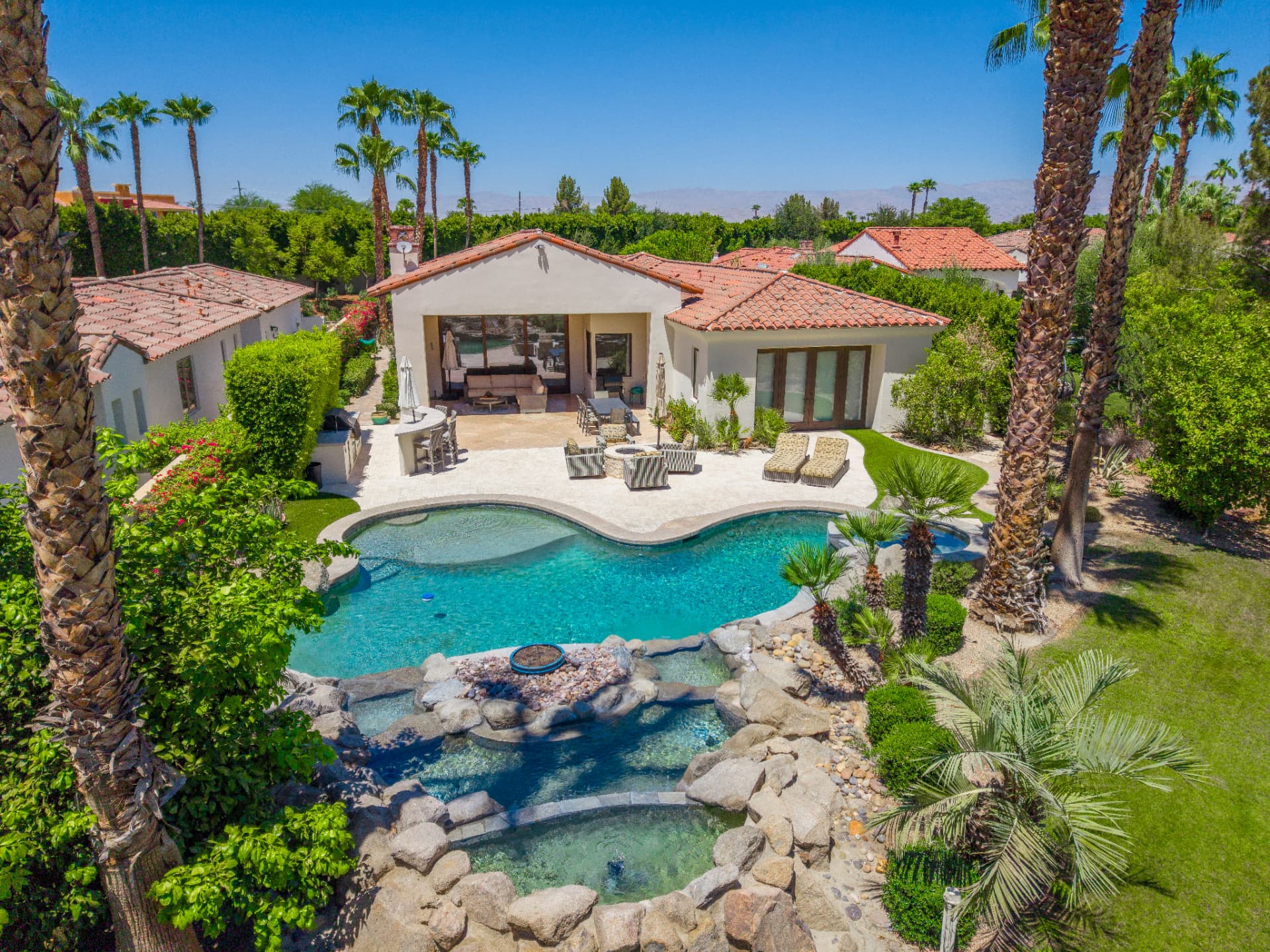 Pool, rock spa and waterfall with palms and mountain views