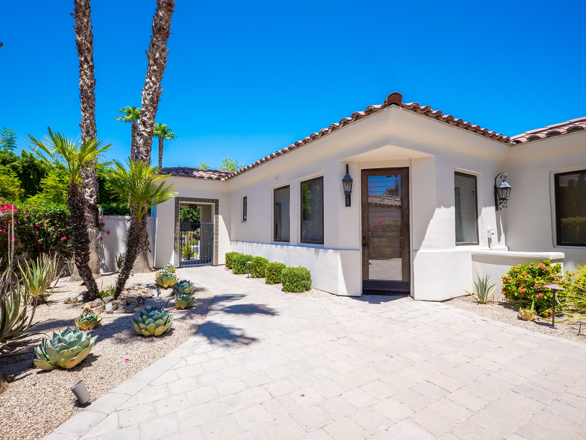 Front elevation with tiled gate, agaves and covered entry