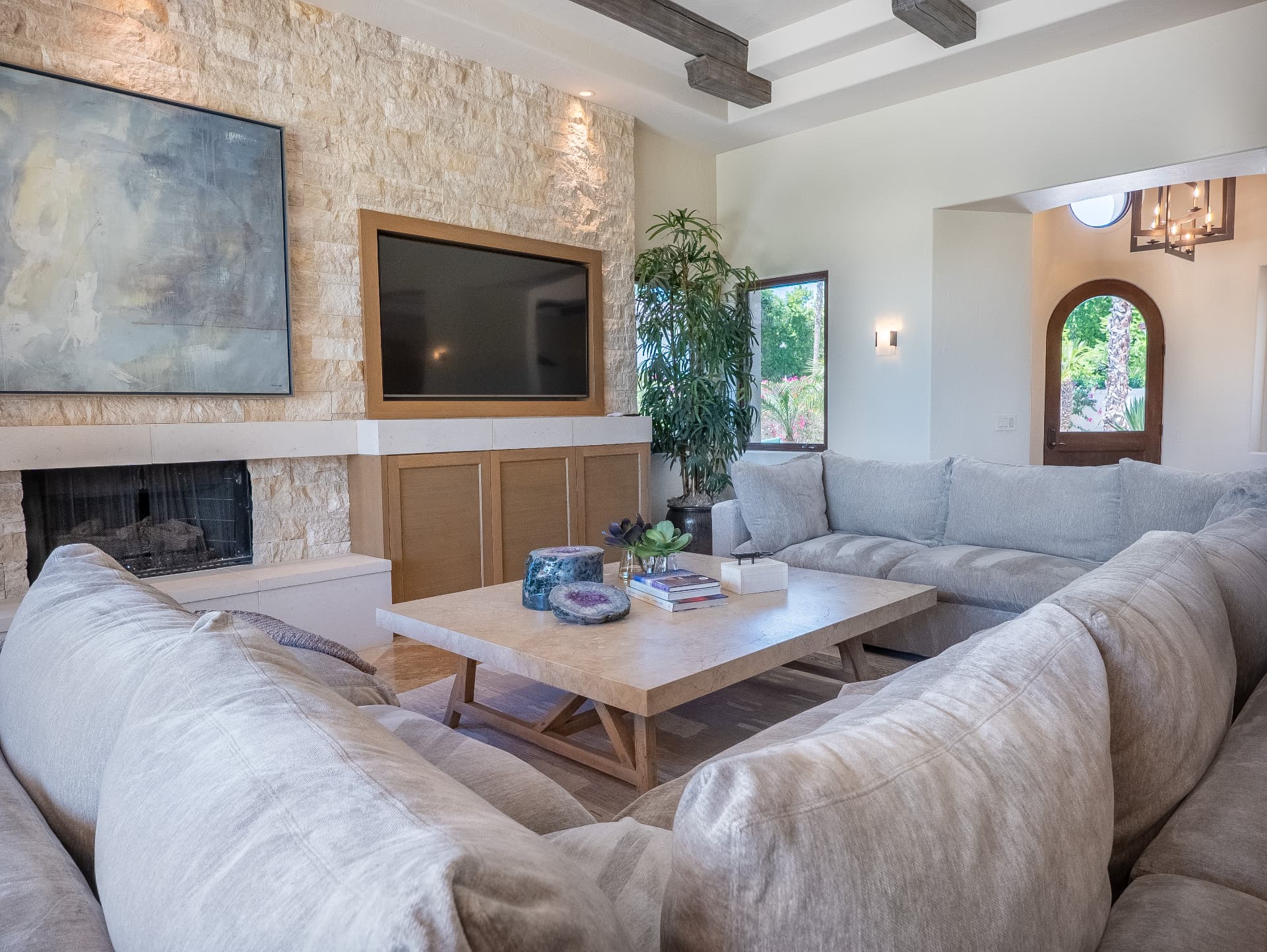 Living room with stone fireplace, linen sectional and travertine table
